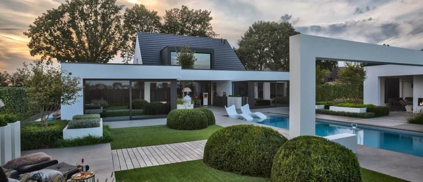 Strak gemaaid gazon langs een zwembad in een luxe tuin in het Gooi